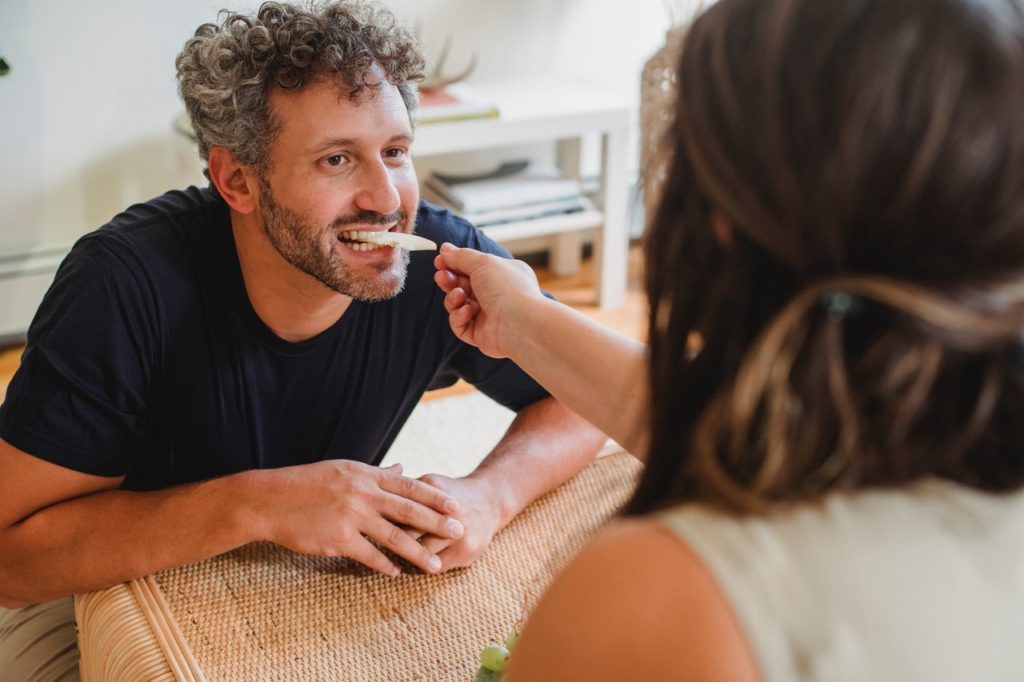 happy man eating food from wife's hand