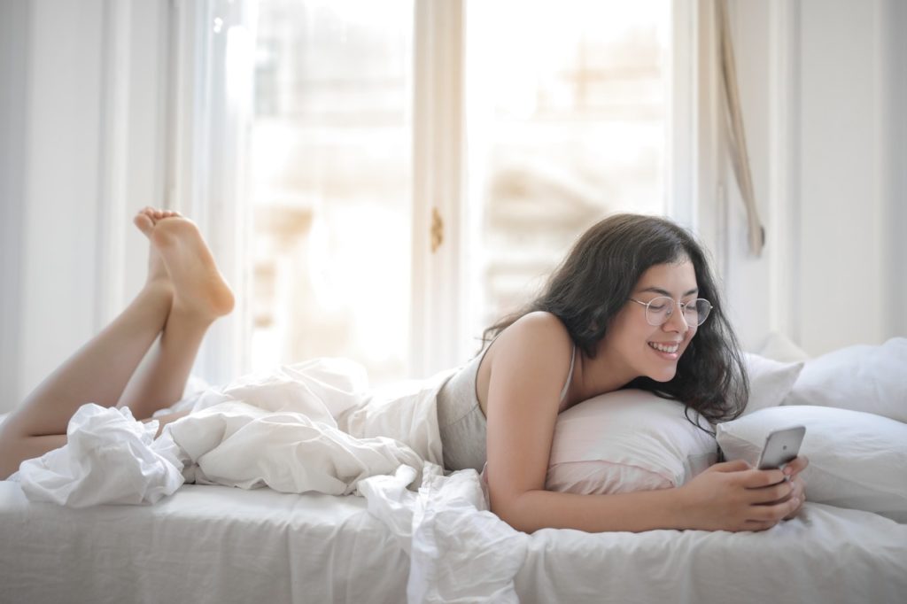 woman texting while lying on bed